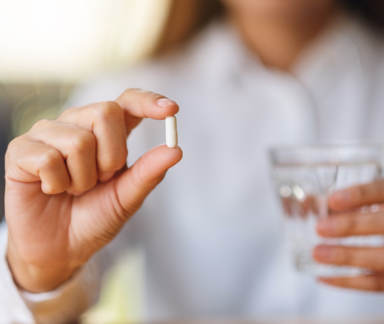 Woman taking a supplement with water